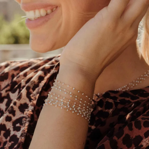 femme souriante portant plusieurs bracelets gigi clozeau or rose résine opale