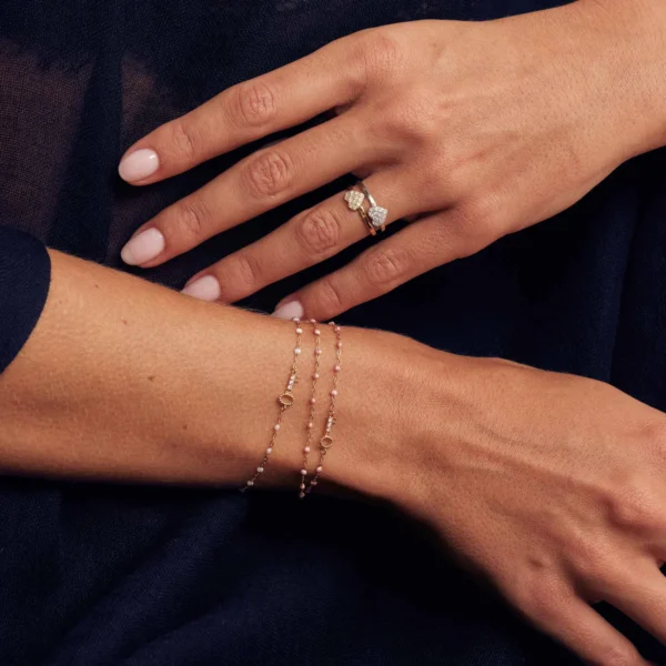 mains de femme habillée en noir portant deux bagues coeur en or et diamants et des bracelets clés en or et diamants