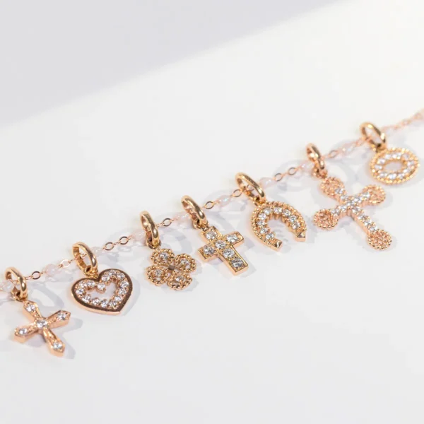 pendentig gigi clozeau en or rose et diamants. différents motifs : croix, coeur, trèfle, fer à cheval
