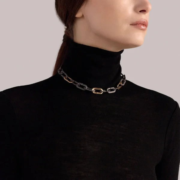 collier vhernier mon jeu en titane et or portée par une femme habillée d'un pull col roulé noir