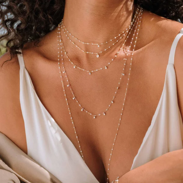 photographie d'une femme à la peau matte portant plusieurs colliers gigi clozeau de plusieurs longueurs résine opale avec diamants