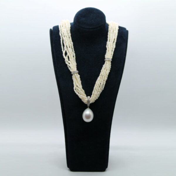 buste bleu marine sur fond blanc et gris, collier perles blanches, or blanc, diamant et perle goutte centrale en pendentif