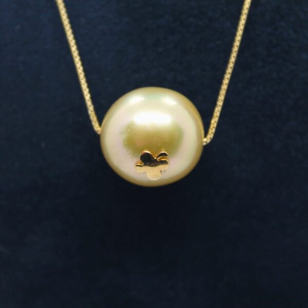zoom sur un collier orné d'une perle gold décorée d'un trèfle à quatre feuilles en or jaune